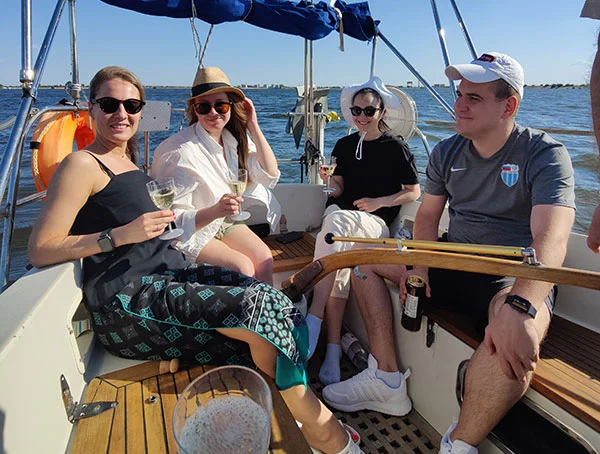 Компания молодых людей с бокалами шампанского на корме яхты